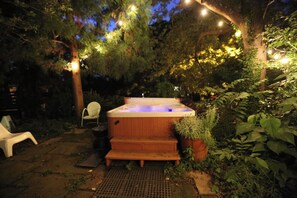 A hot tub surrounded by greenery, with a chair and a small table nearby. - Little Five Points Lodge | Walkable 1BR + Hot Tub (Atlanta)