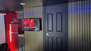 Ein Zimmer mit an der Wand montiertem Fernseher, einer Tür und einem roten Gerät.