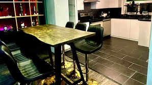 A modern kitchen with a dining area, featuring a table with chairs, a bar area with shelves, and a visible stove. - 1 Red Room private bathroom
In Luxury KIA   A1 (Richmond Hill)