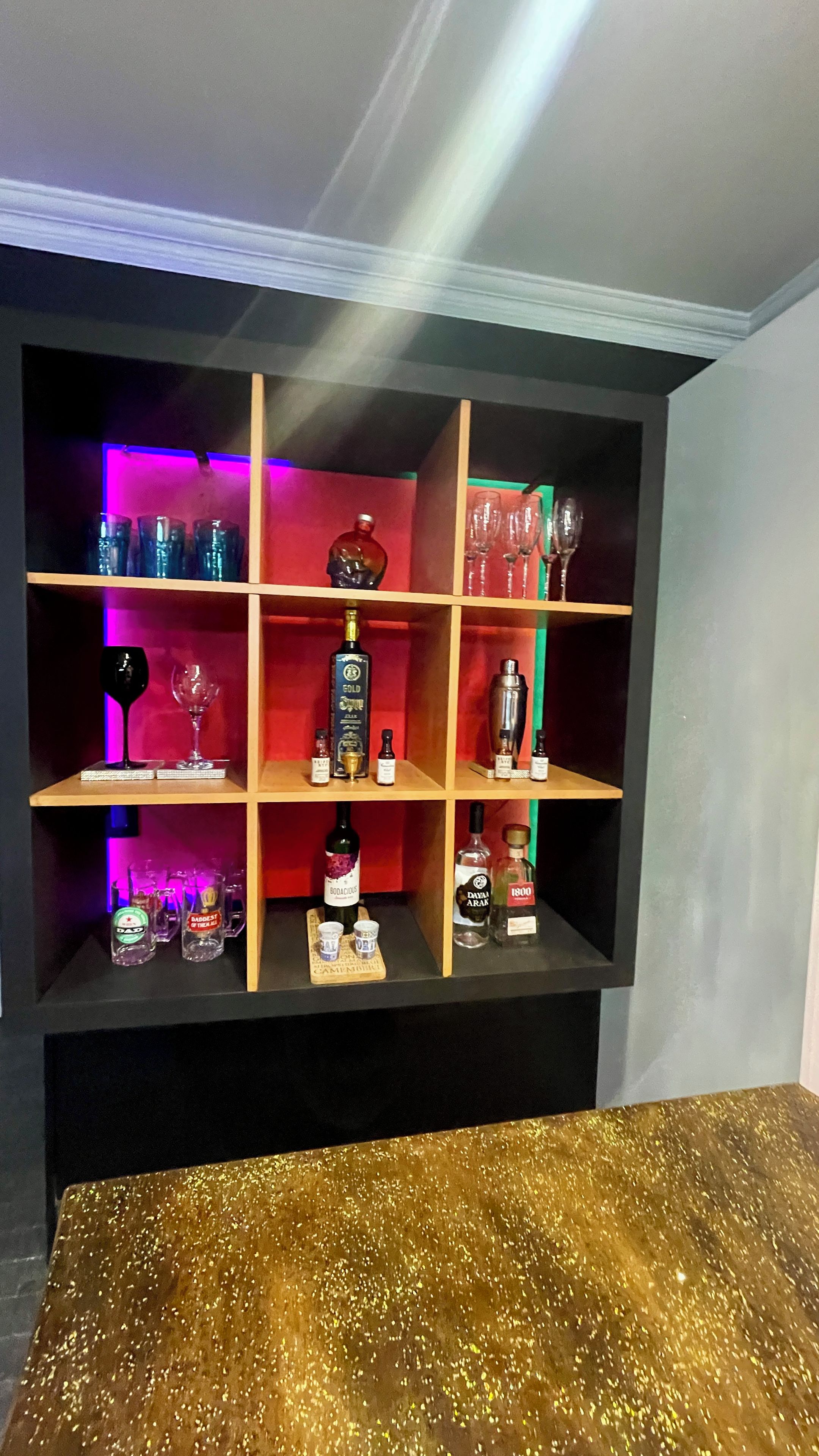 A bar area with shelves containing bottles and glasses.