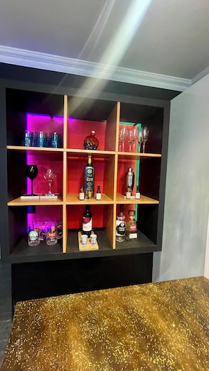 Zona de bar con estantes que contienen botellas y copas.