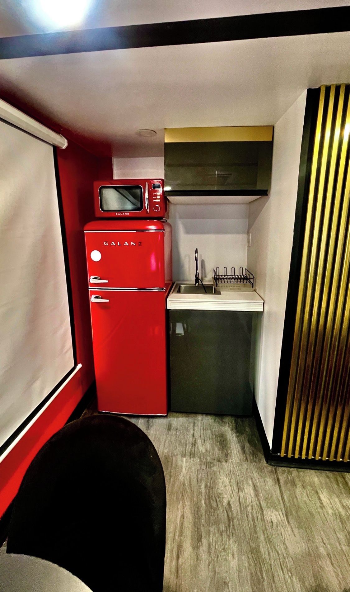 A compact kitchenette with a red refrigerator, a microwave, and a sink.
