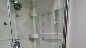 A glass-enclosed shower with a handheld showerhead, a glass door, and a white sink with a mirror. - 1 Red Room private bathroom
In Luxury KIA   A1 (Richmond Hill)