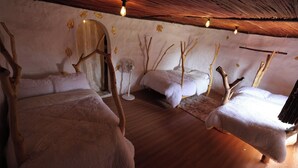 A room with three beds, a fan, and a rustic ceiling. - Maasai Heritage Museum (Kajiado County)