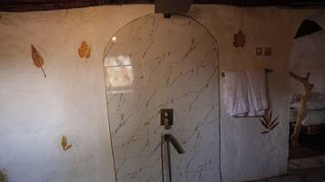 A bathroom with a marble wall, a shower, and a towel rack.