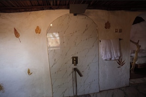 Un baño con pared de mármol, ducha y perchero.