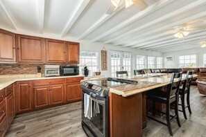 Een ruime keuken met houten kastjes, een groot eiland en een eethoek met lederen zitplaatsen.