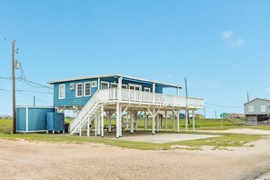 Een twee verdiepingen tellend huis met een veranda en een klein bijgebouw.