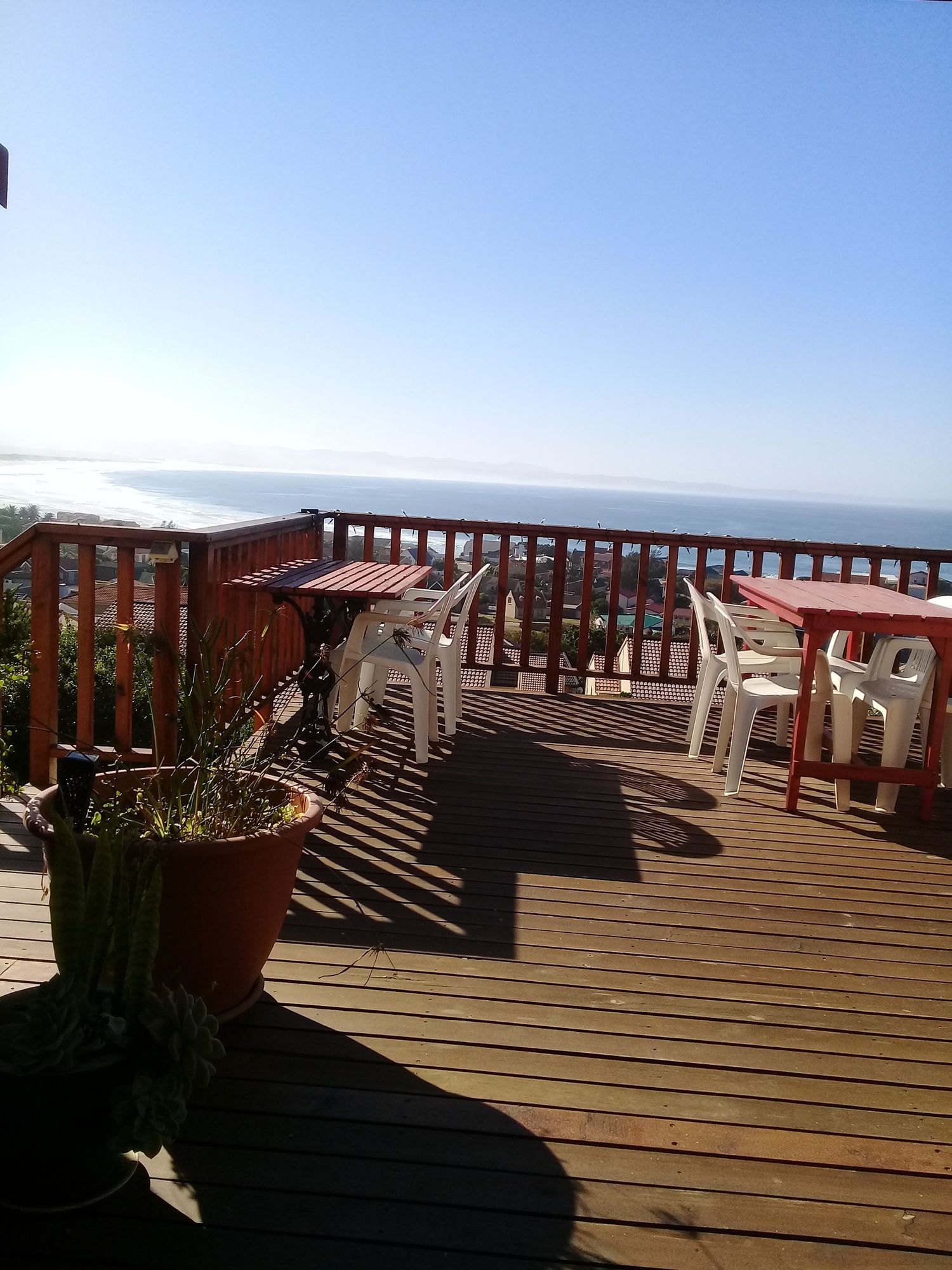 A wooden deck with outdoor furniture, including tables and chairs, overlooking a body of water.