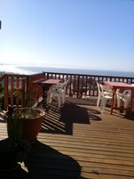 Una terraza de madera con asientos al aire libre, con vista al mar.