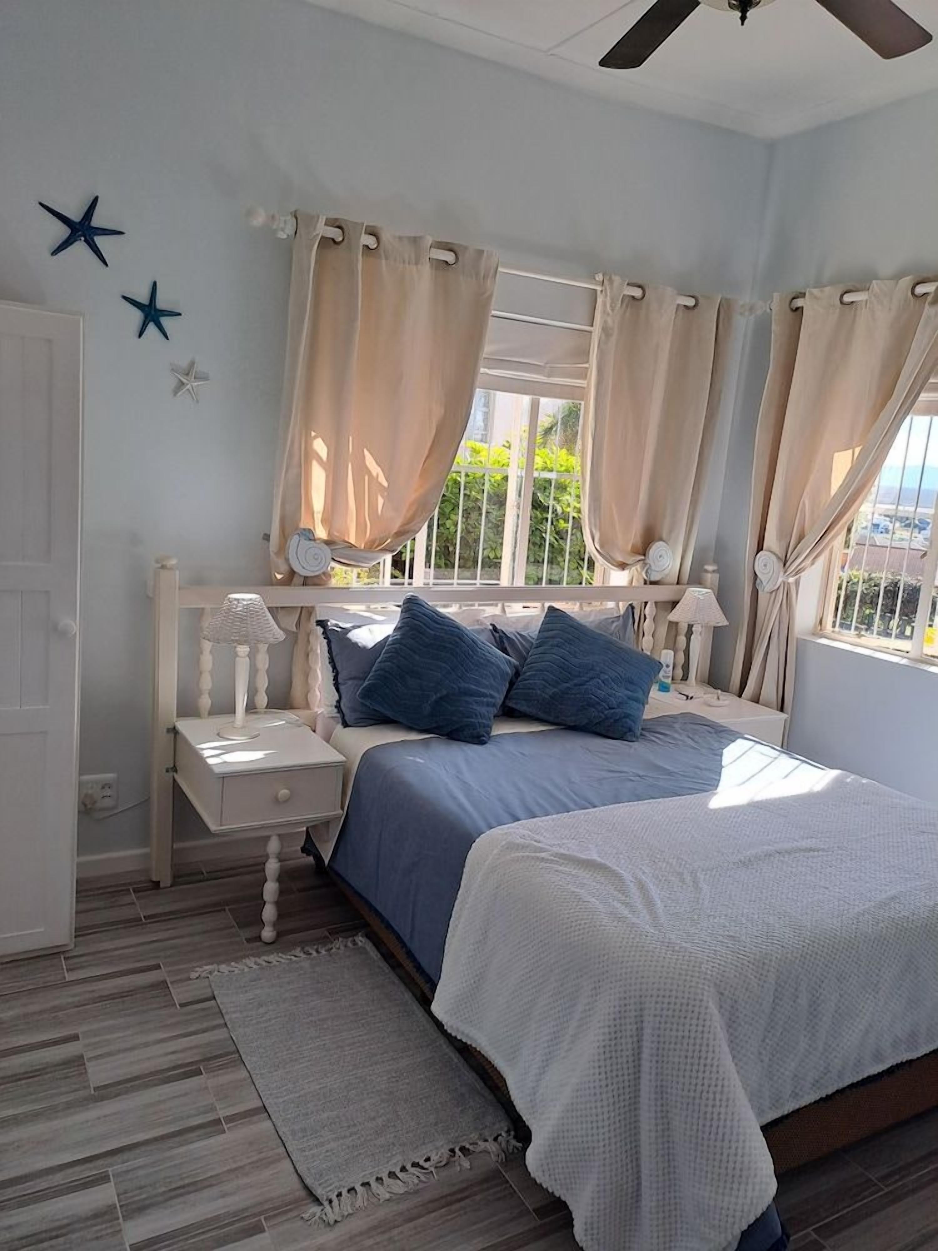 A bedroom with a bed, nightstands, a window with curtains, and star decorations on the wall.