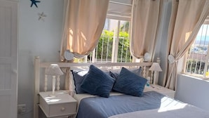 Ein Schlafzimmer mit Bett, Nachttischen, einem Fenster mit Vorhängen und Sternen an der Wand.