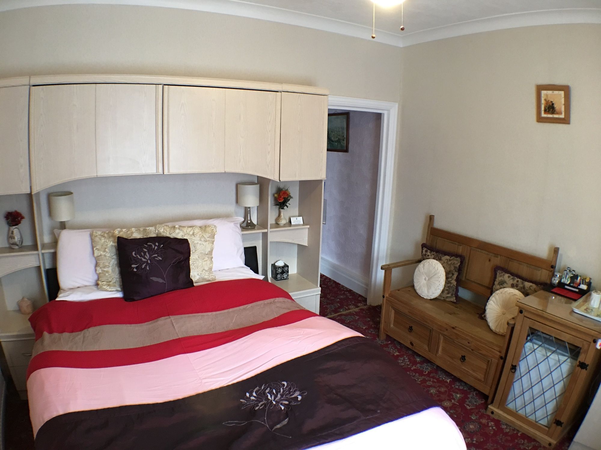 A bedroom with a bed, bedside tables, a nightstand, a dresser, and a mirror.