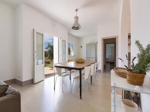 Una cocina moderna con una mesa de comedor y sillas, una lámpara colgante y vistas al exterior a través de un ventanal.