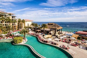 Ein Resort mit einem großen Pool, Palmen und Blick auf den Ozean.