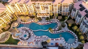 Un complexe hôtelier doté d’une piscine centrale, de nombreux balcons et entouré de palmiers.