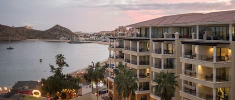 A multi-story hotel with balconies overlooking a beach and the sea.
