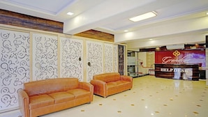 Recepção de hotel com dois sofás, um balcão de atendimento e painéis decorativos.