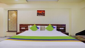 Quarto de hotel com uma cama grande, cabeceira de madeira e uma moldura com um quadro na parede.