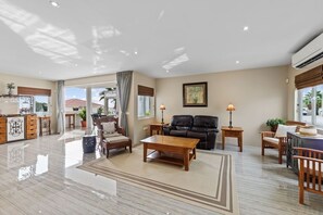 A spacious living area with a sofa, coffee table, and a dining table. There is a kitchen area with cabinets and a refrigerator. - Hibisca Signature Residence with 3 Bedrooms - 2 Baths + Pool (Grote Berg)