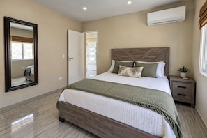 A bedroom with a bed, a nightstand, a mirror, and an air conditioning unit. - Hibisca Signature Residence with 3 Bedrooms - 2 Baths + Pool (Grote Berg)