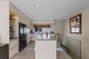 A modern kitchen with a central island, built-in appliances, and a glass railing overlooking a balcony. - Hibisca Signature Residence with 3 Bedrooms - 2 Baths + Pool (Grote Berg)