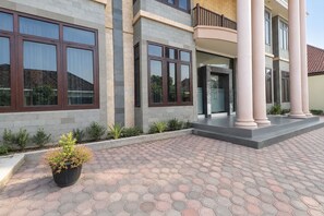 A modern building with large windows, a paved entrance area, and a potted plant. - Townhouse Oak Hotel Grand Puri (Penida Island)
