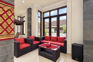 A spacious indoor area with wicker furniture, large windows, and a view of the outside.