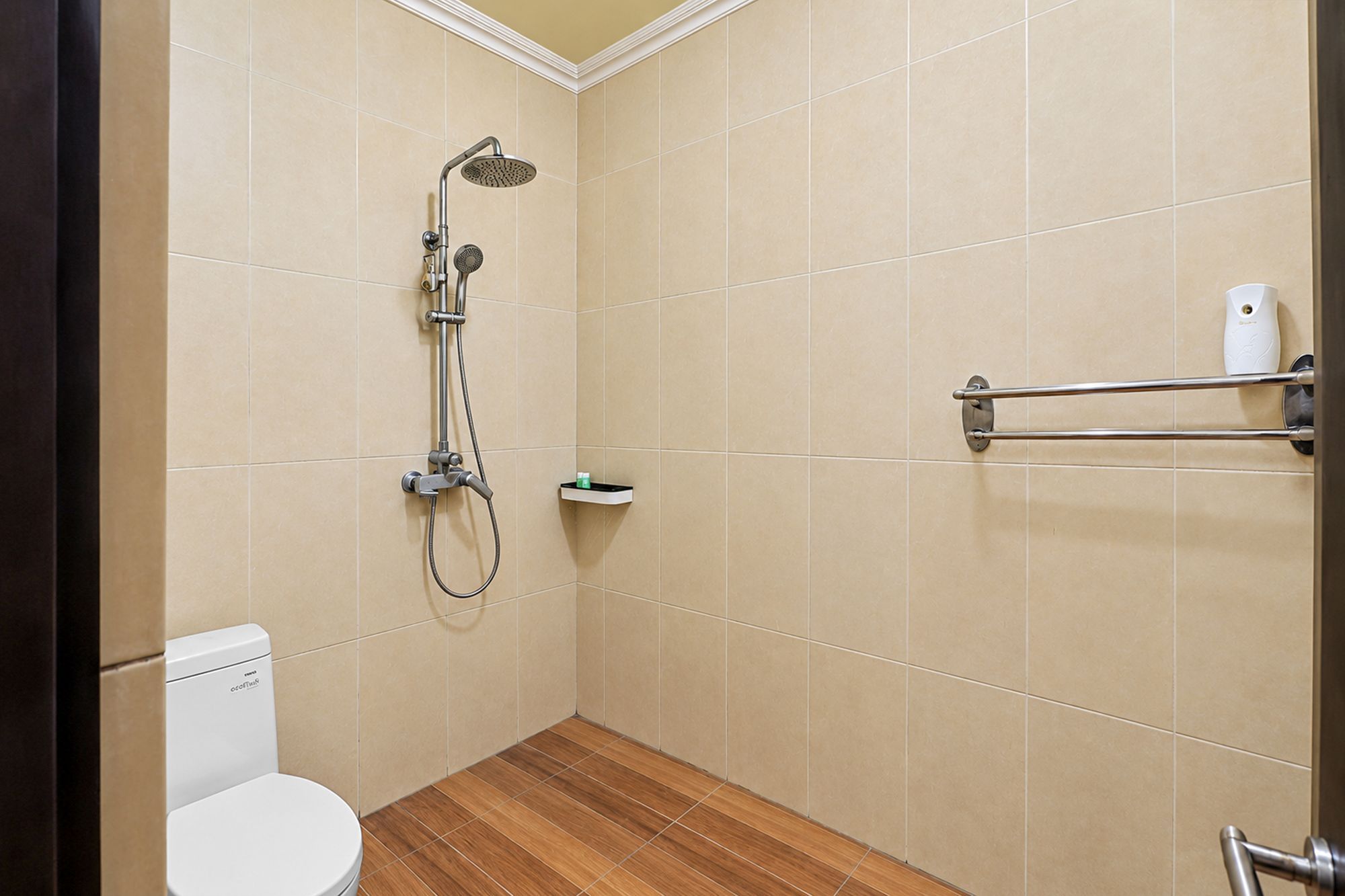 Un baño pequeño con inodoro, ducha con cabezal de ducha manual y toallero.