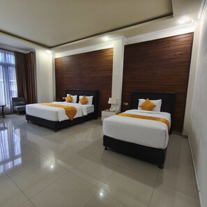 Habitación de hotel con dos camas, una mesita de noche, una lámpara y vistas al exterior.
