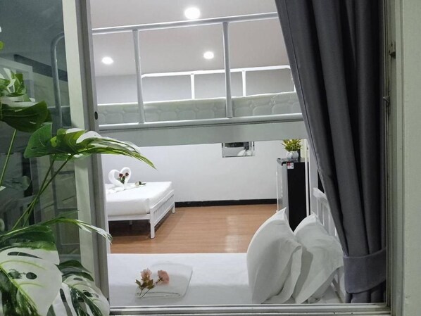 A room with a bed, a small table, a potted plant, and a window with curtains.