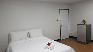 Una habitación de hotel con una cama, una puerta y un refrigerador.