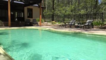 A swimming pool with lounge chairs and a covered seating area.