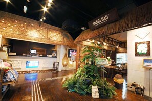 A reception area with a thatched roof, a reception desk, and a large plant centerpiece.