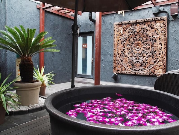 A spa area with a hot tub surrounded by potted plants and a decorative wall panel.
