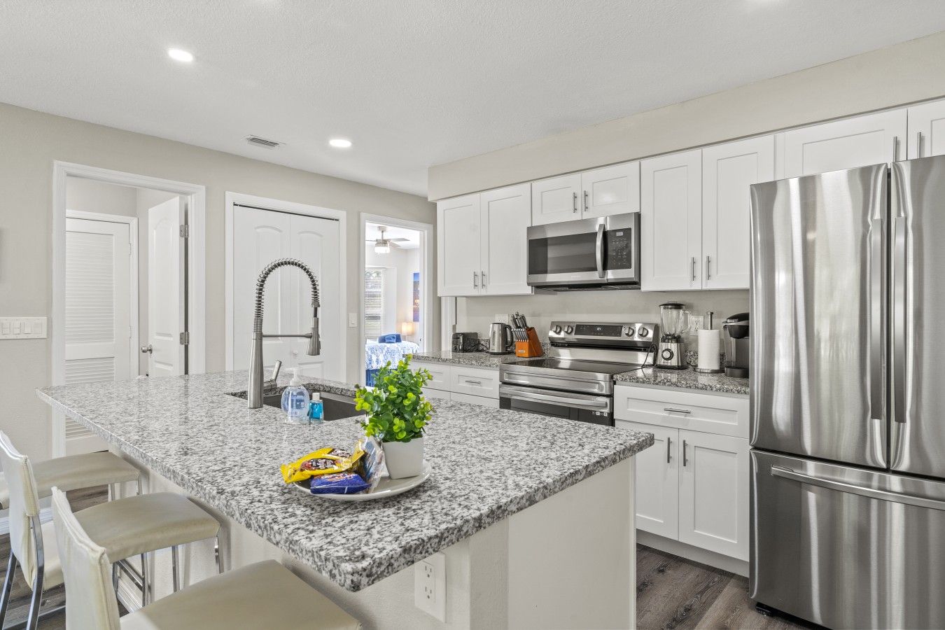 A modern kitchen with white cabinetry, stainless steel appliances, and a granite countertop.