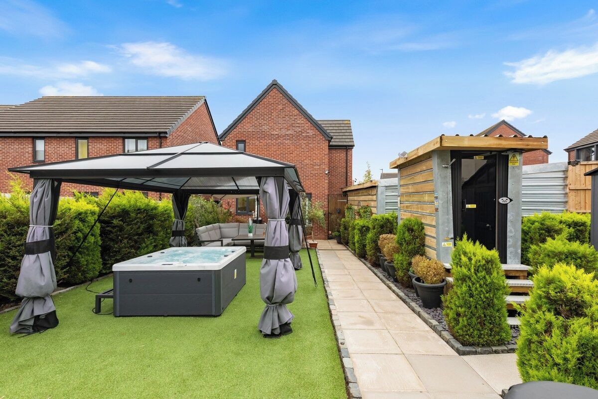 Ein Garten mit Whirlpool, Terrassenmöbeln und einer überdachten Sitzgelegenheit.