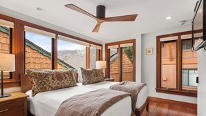 A bedroom with two beds, a ceiling fan, and large windows. - Downtown Aspen Collection by Frias (Aspen)