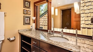 A bathroom with a granite countertop, a sink, a large mirror, and framed pictures on the wall. - Downtown Aspen Collection by Frias (Aspen)