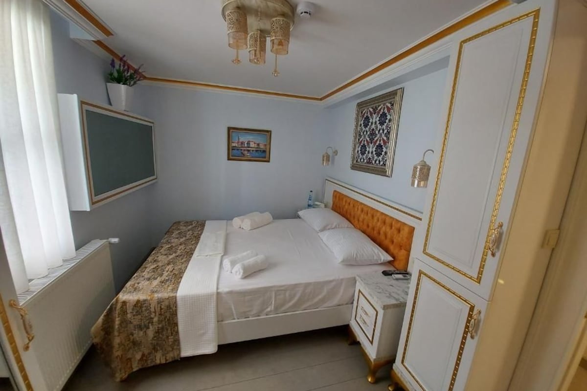 A hotel room with a bed, bedside table, wardrobe, and a television.