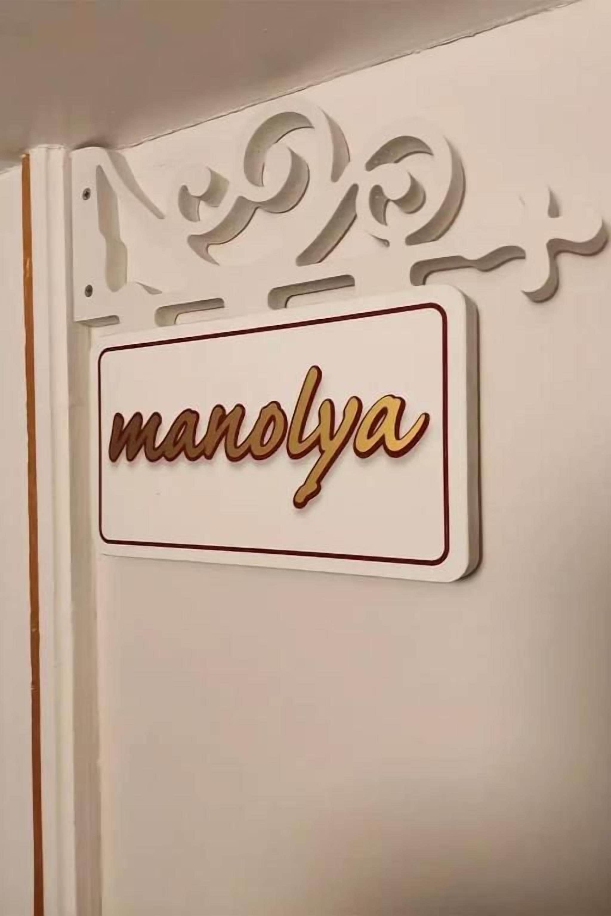 Uma parede com uma placa decorativa que diz 'manolya'.