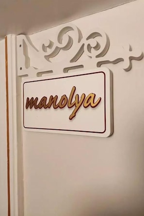 A wall with a decorative sign that reads 'manolya'.