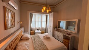 Una habitación de hotel con cama, escritorio, silla, espejo y ventana con cortinas.