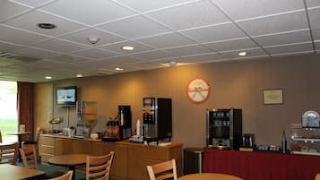 Un espace repas avec des tables et des chaises en bois, un coin café et une horloge au mur.
