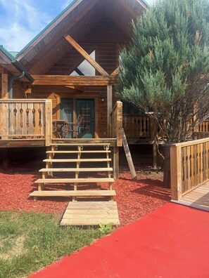 Eine Holzhütte mit einer Veranda, einer Tür und einer kleinen Treppe, die zu ihr hinaufführt.