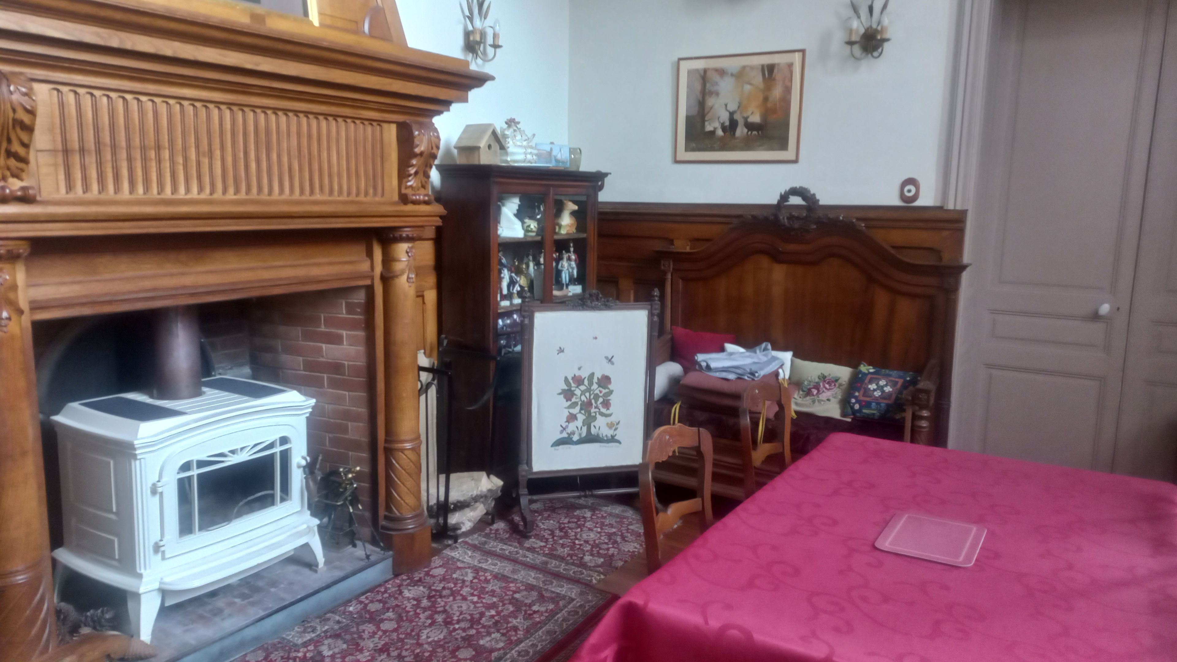 A room with a fireplace, a bed with a pink bedspread, a wooden cabinet, and a framed picture on the wall.