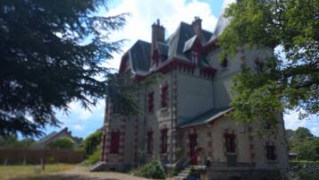 Un grand bâtiment historique, doté de nombreuses cheminées et d’une entrée imposante.