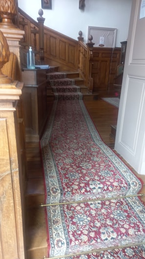 Una escalera con alfombra roja que conduce a una puerta de madera.
