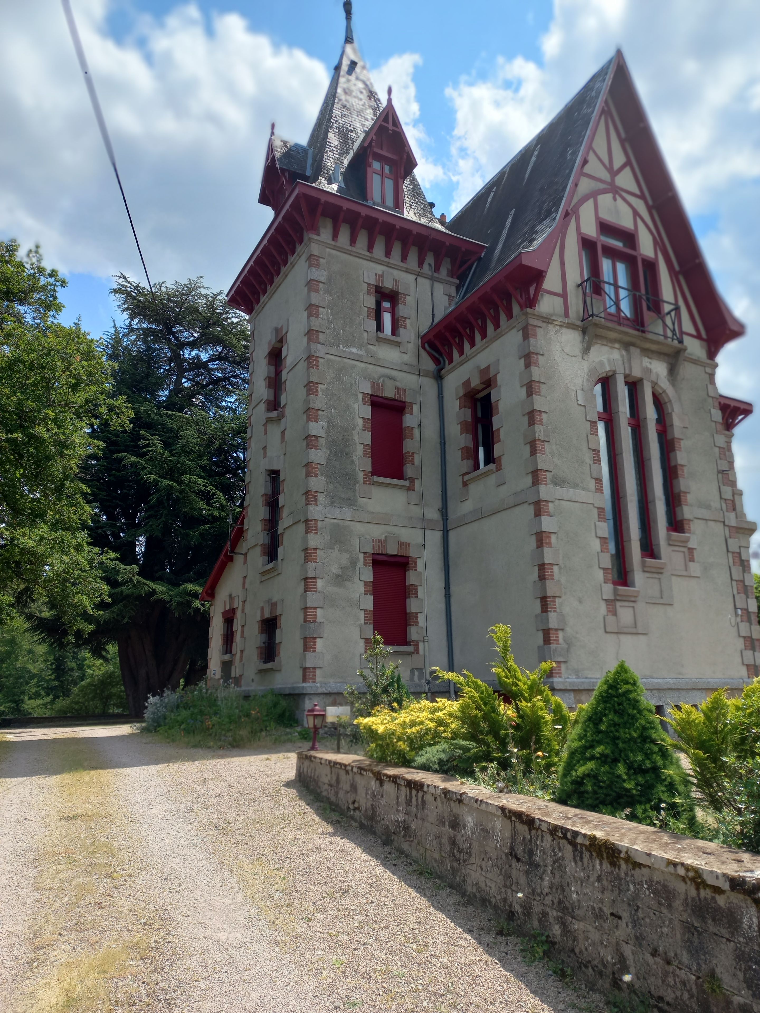 A historic building with a steeply pitched roof, red window frames, and a prominent tower.