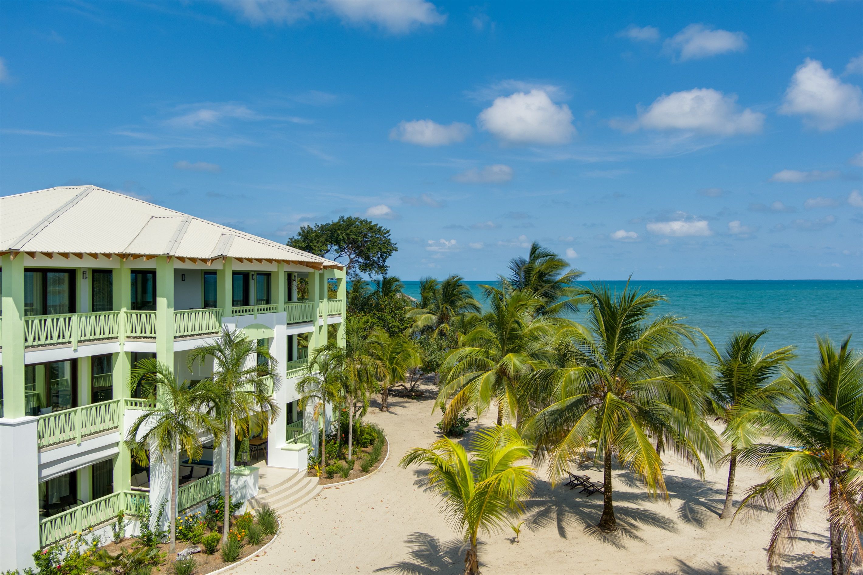Un resort con vista a la playa, varios pisos y palmeras.